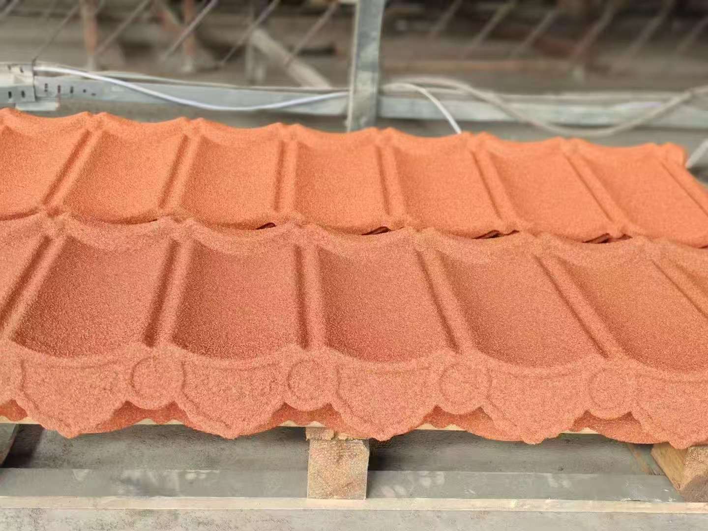 Close-up of a textured metal rooftop featuring a red vent structure, captured at sunset enhancing shadows.